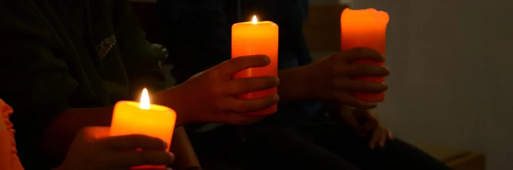 Kinderhände halten brennende Kerzen in der Regulakirche